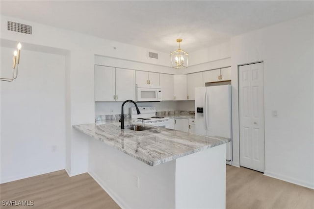 kitchen with white appliances, a sink, a peninsula, and light wood-style flooring