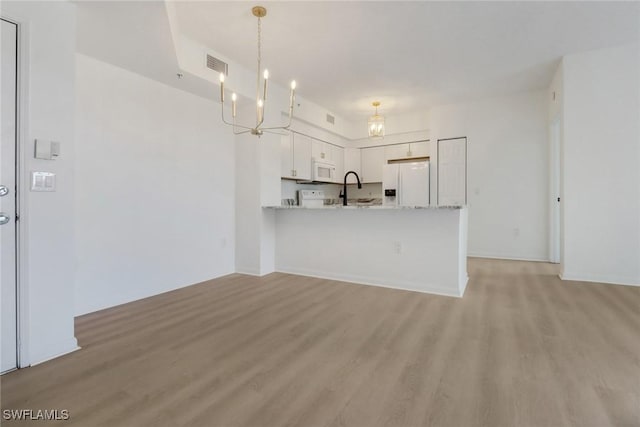 kitchen featuring white appliances, light countertops, light wood-type flooring, and a peninsula