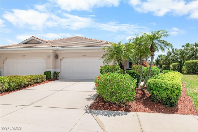 view of front of house with concrete driveway, stucco siding, a tile roof, and a garage