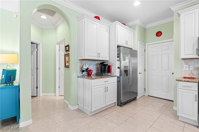 kitchen with light tile patterned floors, stainless steel fridge, white cabinetry, and tasteful backsplash