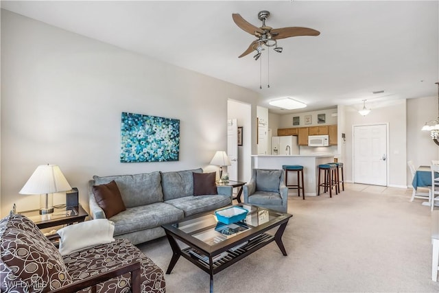 living room featuring light carpet, baseboards, and a ceiling fan