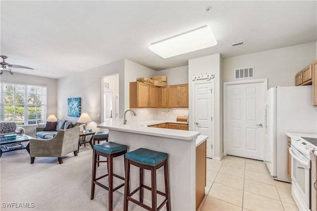 kitchen featuring a breakfast bar, white electric range, open floor plan, and visible vents