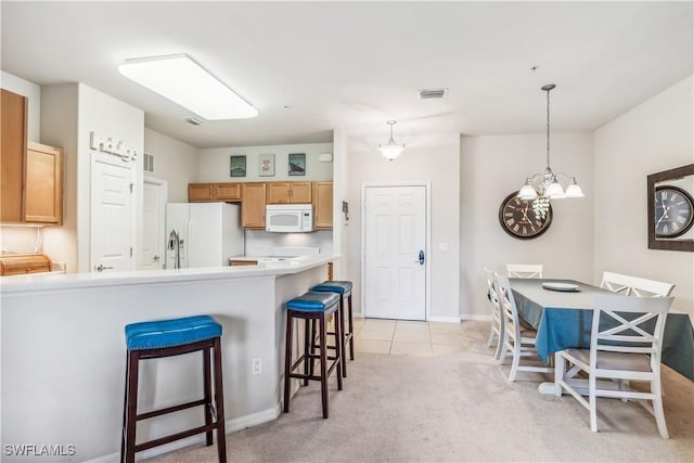 kitchen featuring visible vents, white appliances, a kitchen bar, light countertops, and a chandelier