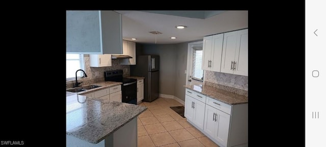 321 Dania St, Lehigh Acres, FL 33936 - kitchen with electric range oven, freestanding refrigerator, a sink, tasteful backsplash, and baseboards