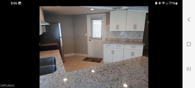 321 Dania St, Lehigh Acres, FL 33936 - kitchen with backsplash, baseboards, white cabinetry, and light stone counters