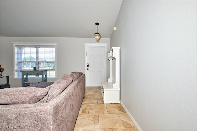living area with light stone finish floors, lofted ceiling, and baseboards