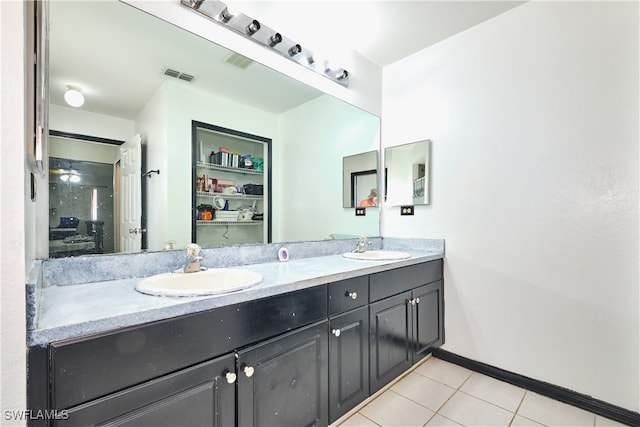 full bath with double vanity, tile patterned floors, baseboards, and a spacious closet