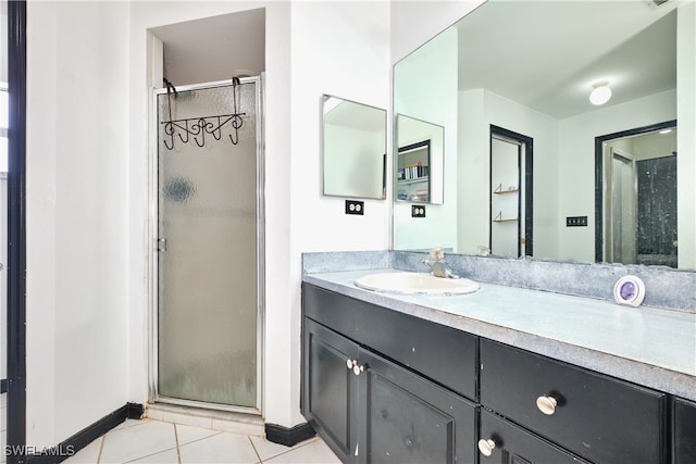 full bathroom with a stall shower, tile patterned flooring, vanity, and baseboards
