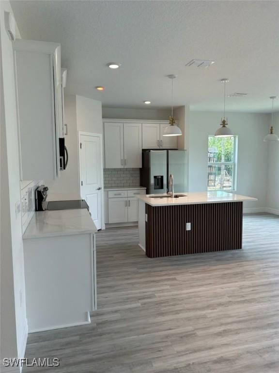 5525 Berryman St, Lehigh Acres, FL 33971 - kitchen featuring stove, an island with sink, stainless steel fridge, light wood-type flooring, and tasteful backsplash