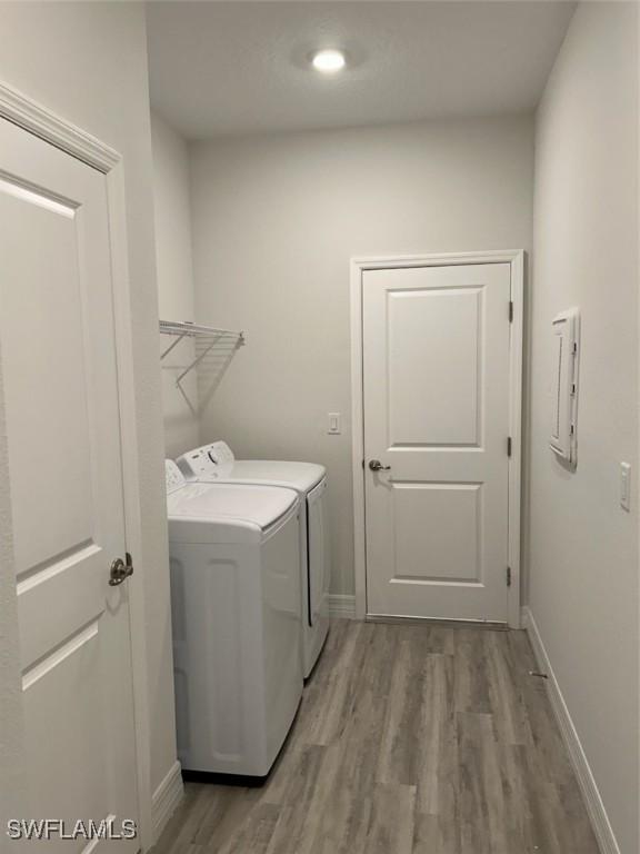 5525 Berryman St, Lehigh Acres, FL 33971 - washroom featuring laundry area, light wood-style flooring, baseboards, and washer and dryer