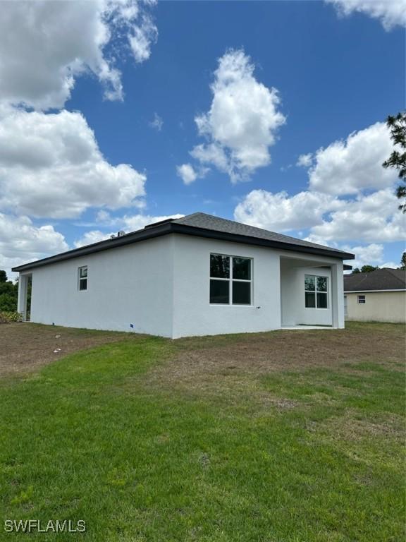 5525 Berryman St, Lehigh Acres, FL 33971 - rear view of house featuring stucco siding and a yard