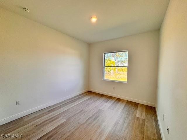 spare room featuring baseboards and wood finished floors