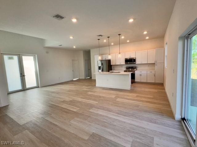 kitchen with white cabinets, appliances with stainless steel finishes, visible vents, and open floor plan