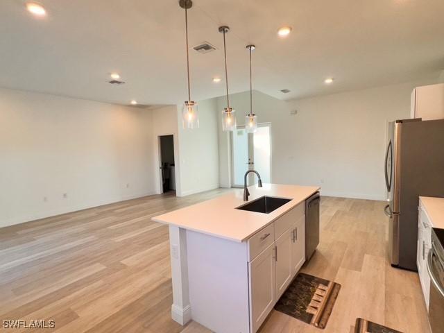 kitchen featuring a sink, stainless steel appliances, light wood-type flooring, visible vents, and light countertops