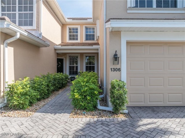entrance to property with a garage and stucco siding