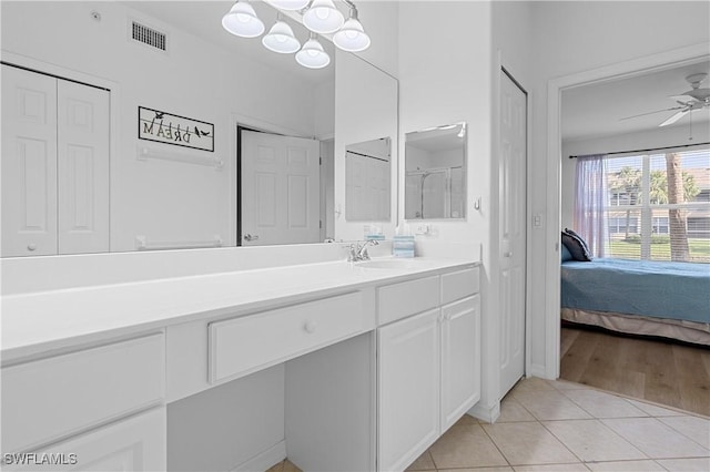 ensuite bathroom with visible vents, tile patterned flooring, vanity, a closet, and ceiling fan with notable chandelier