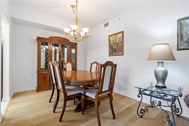 dining space with visible vents, light wood finished floors, baseboards, and an inviting chandelier