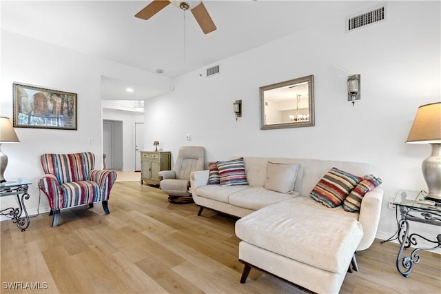living room with ceiling fan, visible vents, baseboards, and light wood-style floors