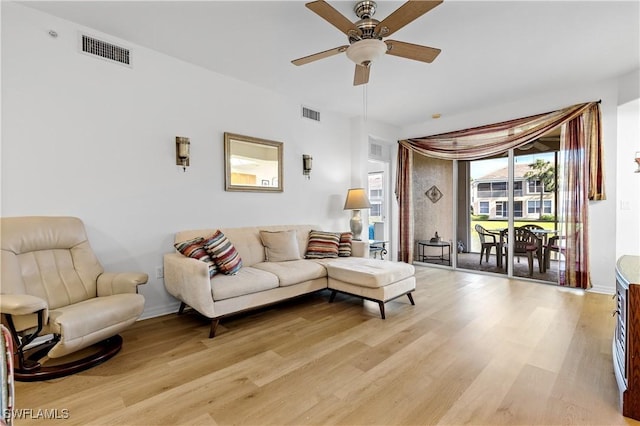 living room featuring light wood-style floors, a ceiling fan, and visible vents