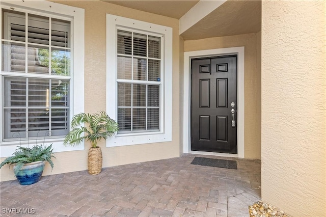 entrance to property featuring covered porch and stucco siding
