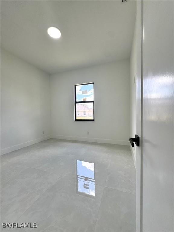 unfurnished room with baseboards and concrete flooring
