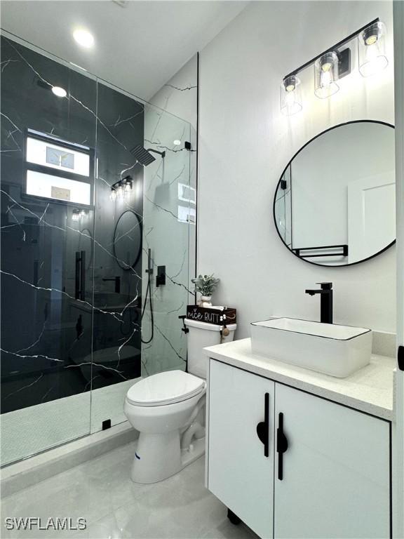 bathroom with vanity, a marble finish shower, and toilet