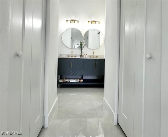 full bathroom featuring double vanity and baseboards
