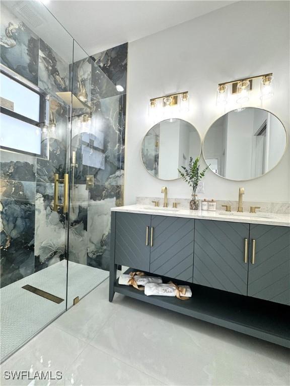 full bath featuring double vanity, a sink, a marble finish shower, and marble finish floor