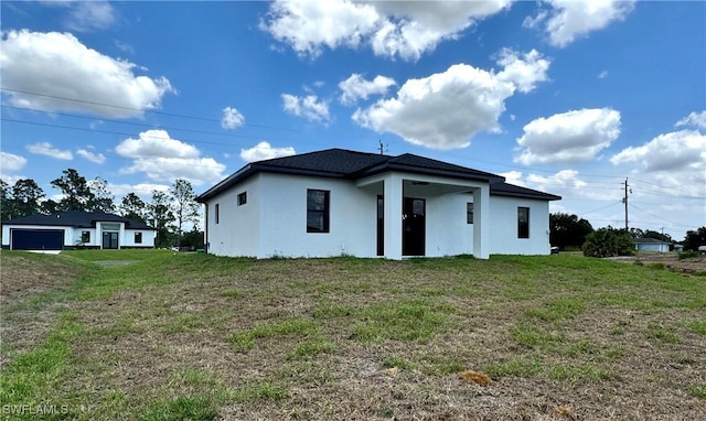rear view of property featuring a lawn and stucco siding