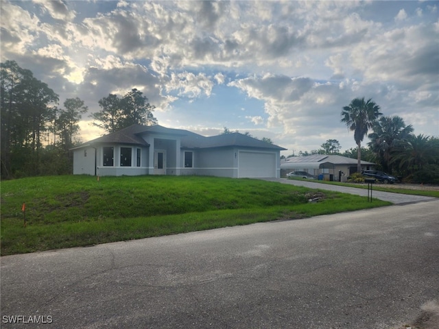 single story home with stucco siding, driveway, a front lawn, and a garage