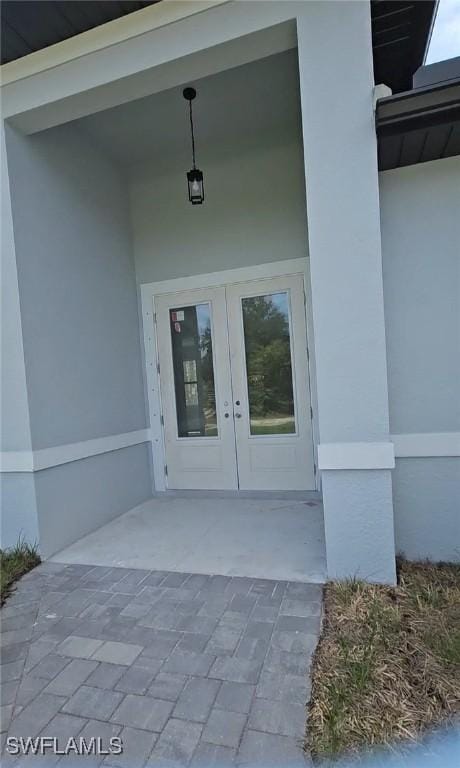 view of exterior entry featuring stucco siding and french doors