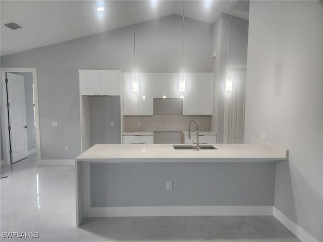 kitchen featuring finished concrete flooring, a peninsula, modern cabinets, white cabinetry, and a sink