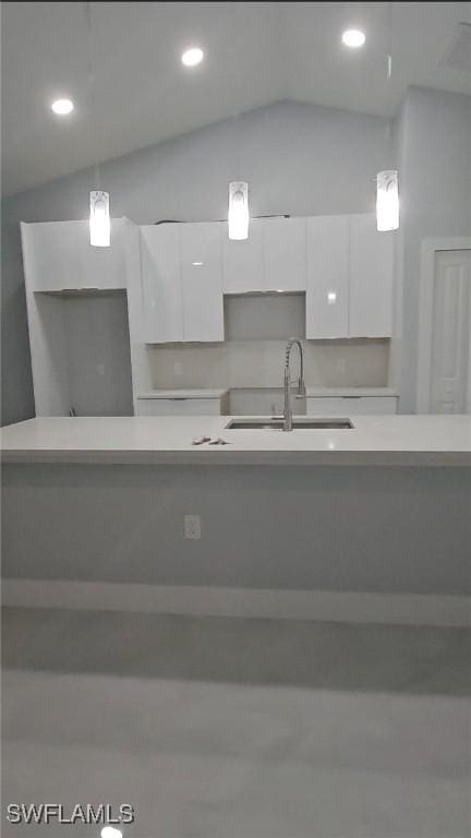 kitchen featuring modern cabinets, vaulted ceiling, a sink, light countertops, and white cabinetry