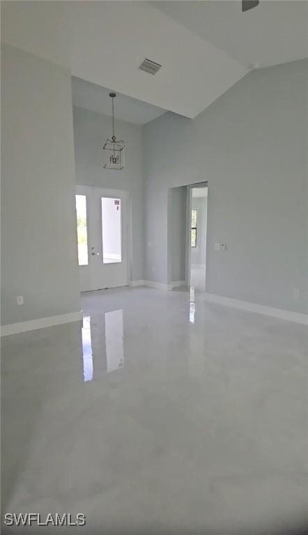 empty room with visible vents, finished concrete flooring, lofted ceiling, and baseboards