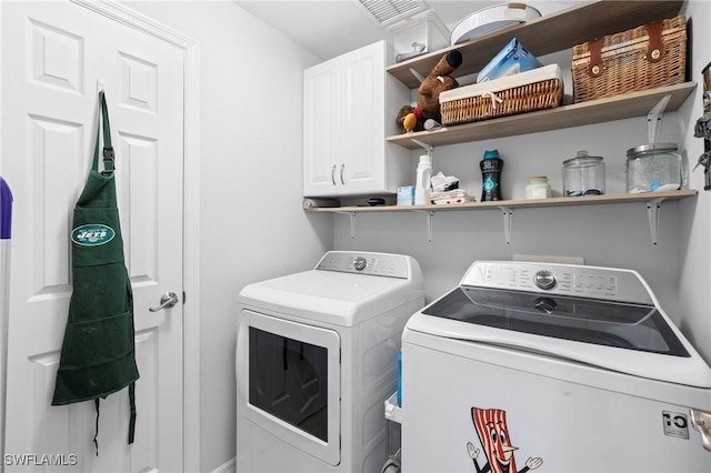 laundry area with separate washer and dryer, visible vents, and cabinet space
