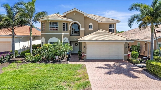 mediterranean / spanish house featuring driveway, stucco siding, a tiled roof, and an attached garage