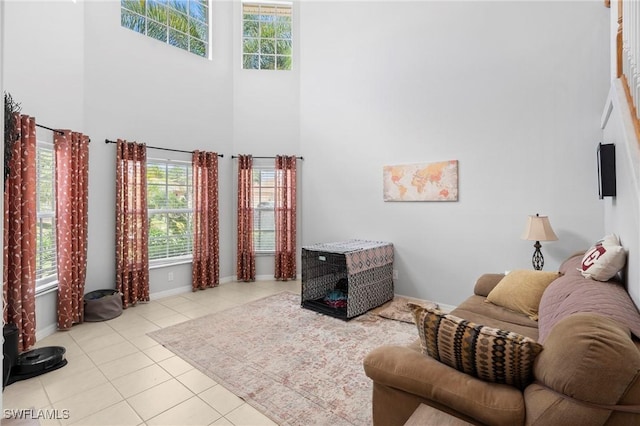 living area featuring tile patterned flooring, a high ceiling, baseboards, and a wealth of natural light