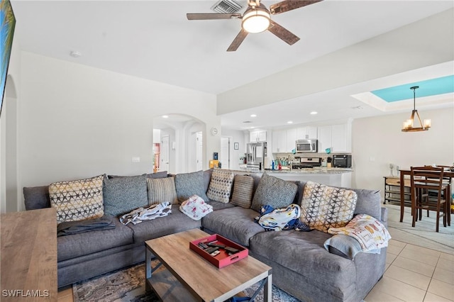 living area featuring light tile patterned floors, ceiling fan with notable chandelier, arched walkways, and recessed lighting