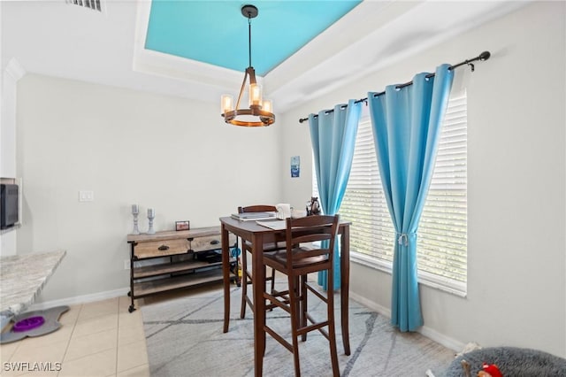 dining space featuring light tile patterned flooring, visible vents, a chandelier, a raised ceiling, and baseboards