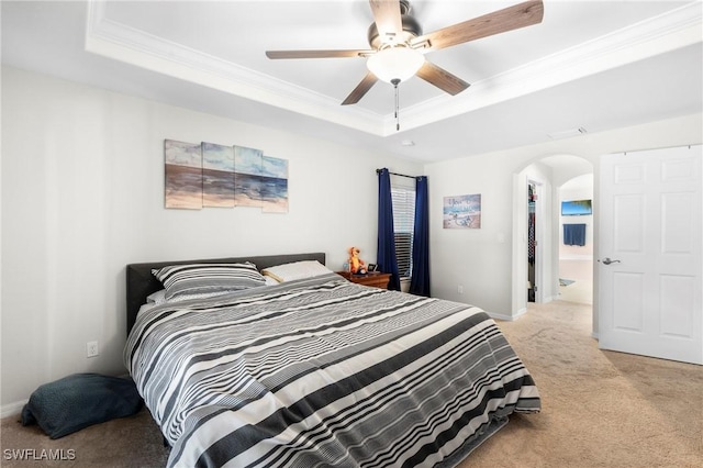 bedroom with a tray ceiling, crown molding, light carpet, and arched walkways