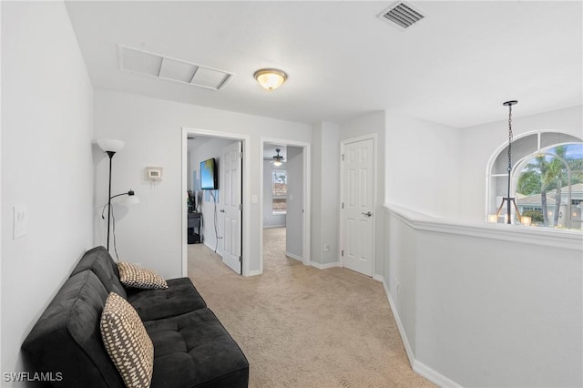 living area featuring visible vents, baseboards, and light carpet