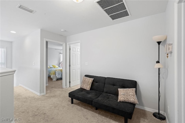 living area with baseboards, visible vents, and light colored carpet