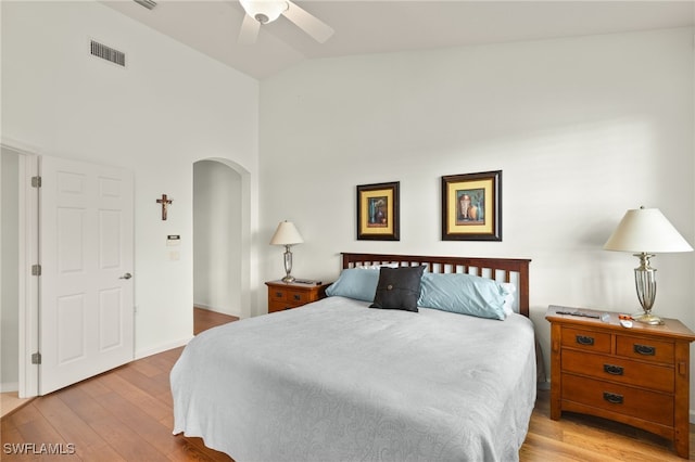 bedroom with arched walkways, a ceiling fan, baseboards, wood finished floors, and visible vents