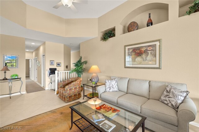 tiled living room featuring baseboards, a ceiling fan, and a towering ceiling