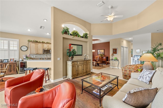 living area with visible vents, a ceiling fan, wine cooler, and a high ceiling