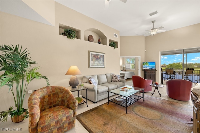 living area featuring visible vents, a ceiling fan, a towering ceiling, and a healthy amount of sunlight