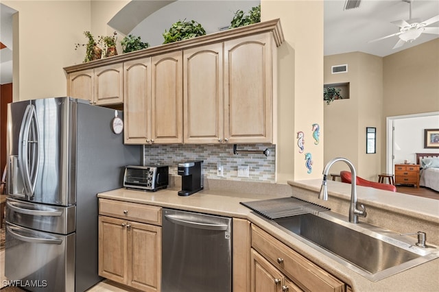 kitchen with a sink, light brown cabinetry, stainless steel appliances, and a toaster
