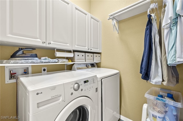 laundry room featuring washing machine and clothes dryer, a textured wall, and cabinet space