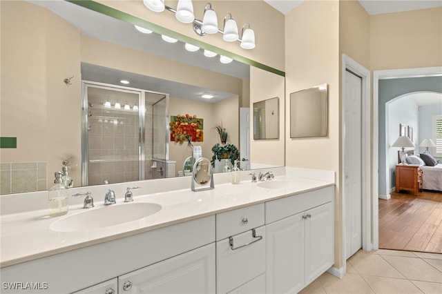 ensuite bathroom with a sink, tile patterned flooring, a shower stall, and double vanity