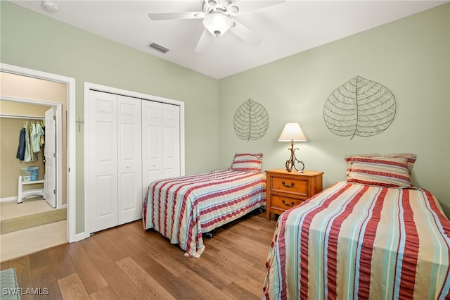 bedroom featuring ceiling fan, baseboards, wood finished floors, visible vents, and a closet